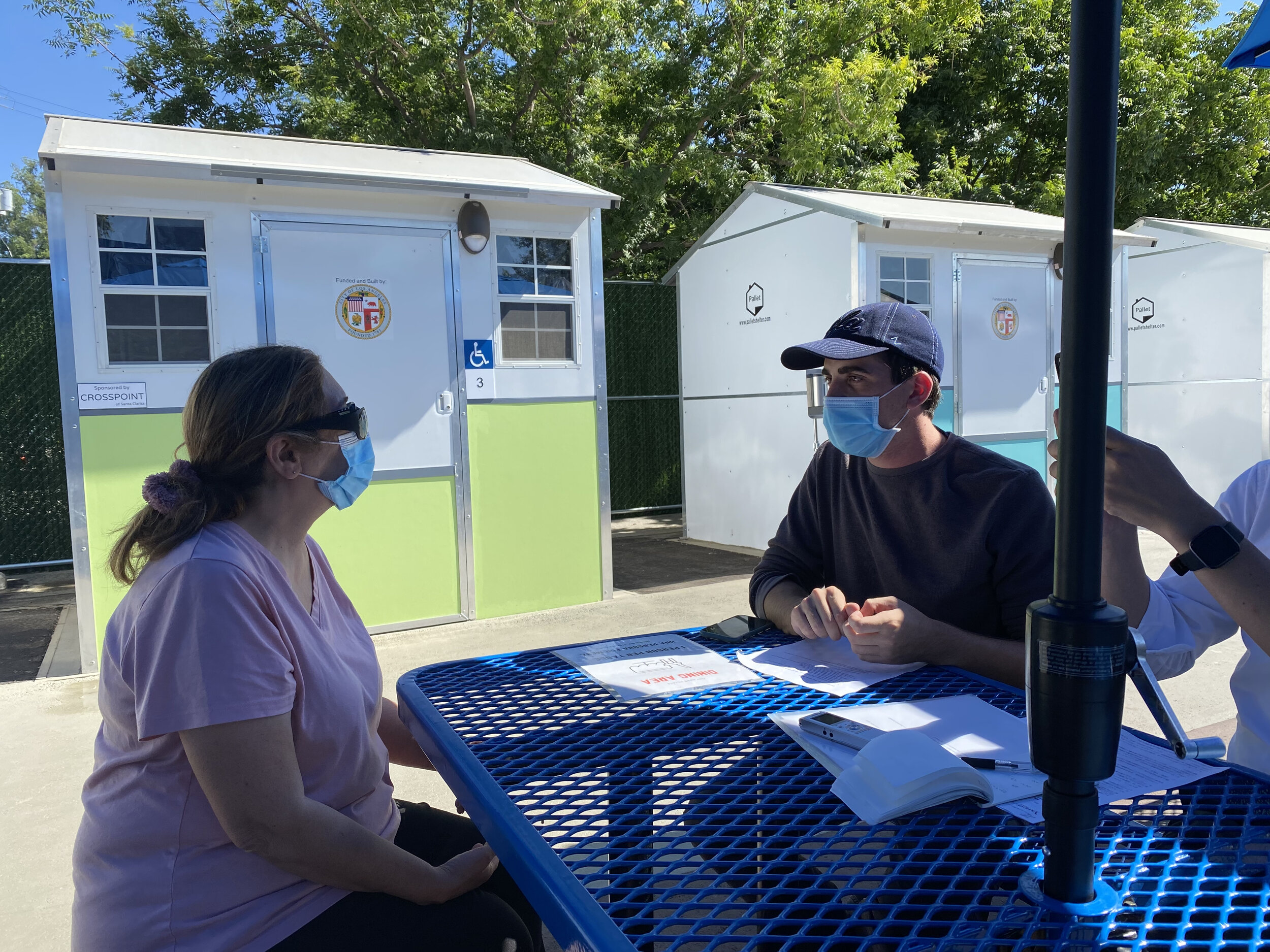Roya talks with a Hope  of the Valley Rescue Mission case manager at Reseda Tiny Home Village in Los Angeles, CA