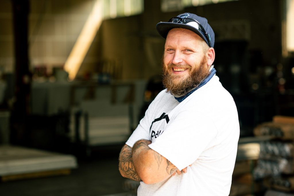 Pallet production supervisor J.J. stands with his arms crossed at Pallet headquarters