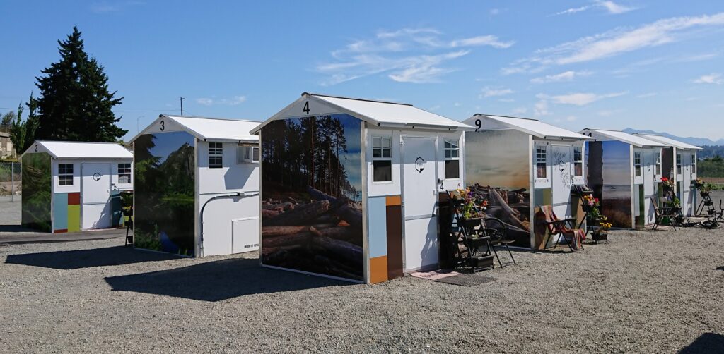 Three rows of Pallet shelters with vinyl wrapping of scenes from the Pacific Northwest