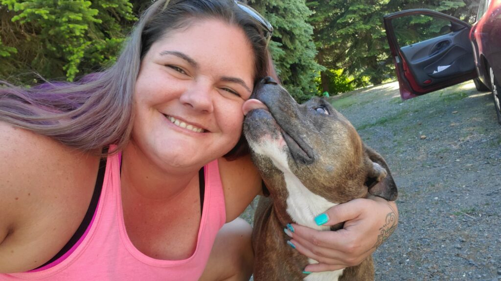 Jennifer embraces her dog Bailey while Bailey is licking her face.