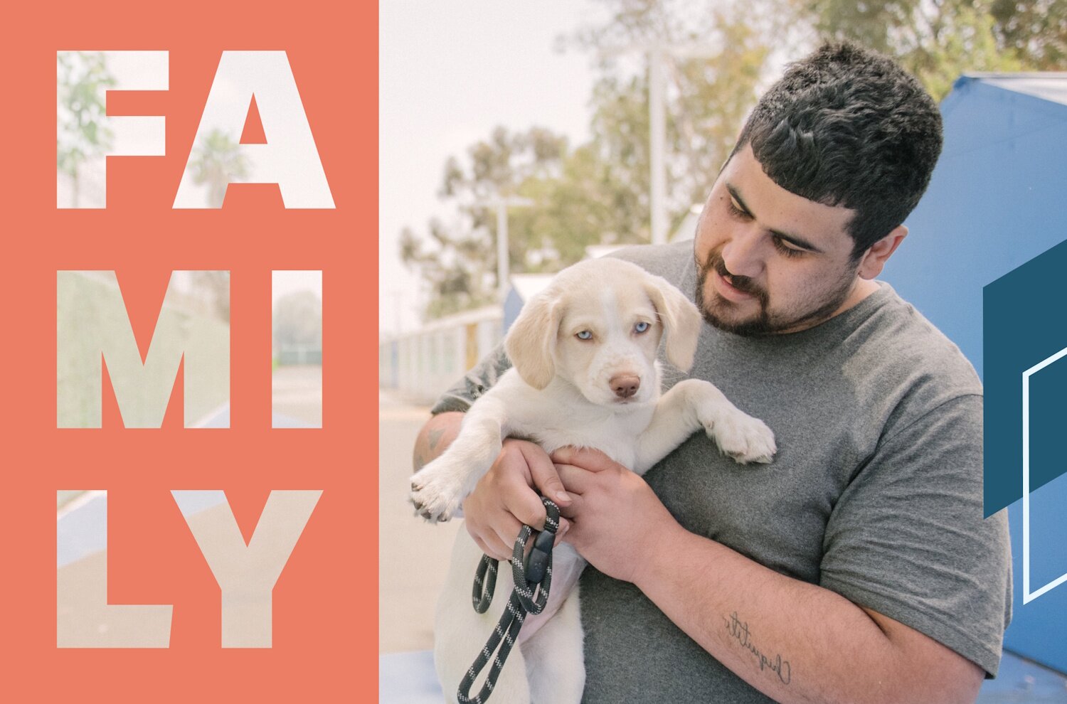 A man wearing a plain t-shirt holds a puppy with bright blue eyes.