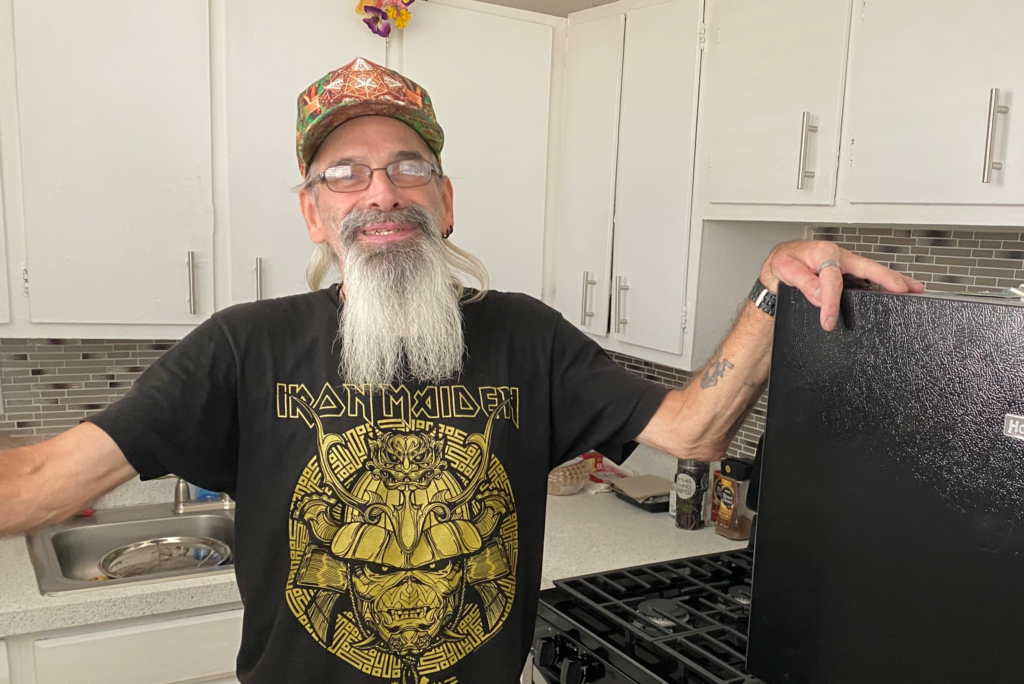 Tim shown from the waist up standing in the kitchen of his new apartment.